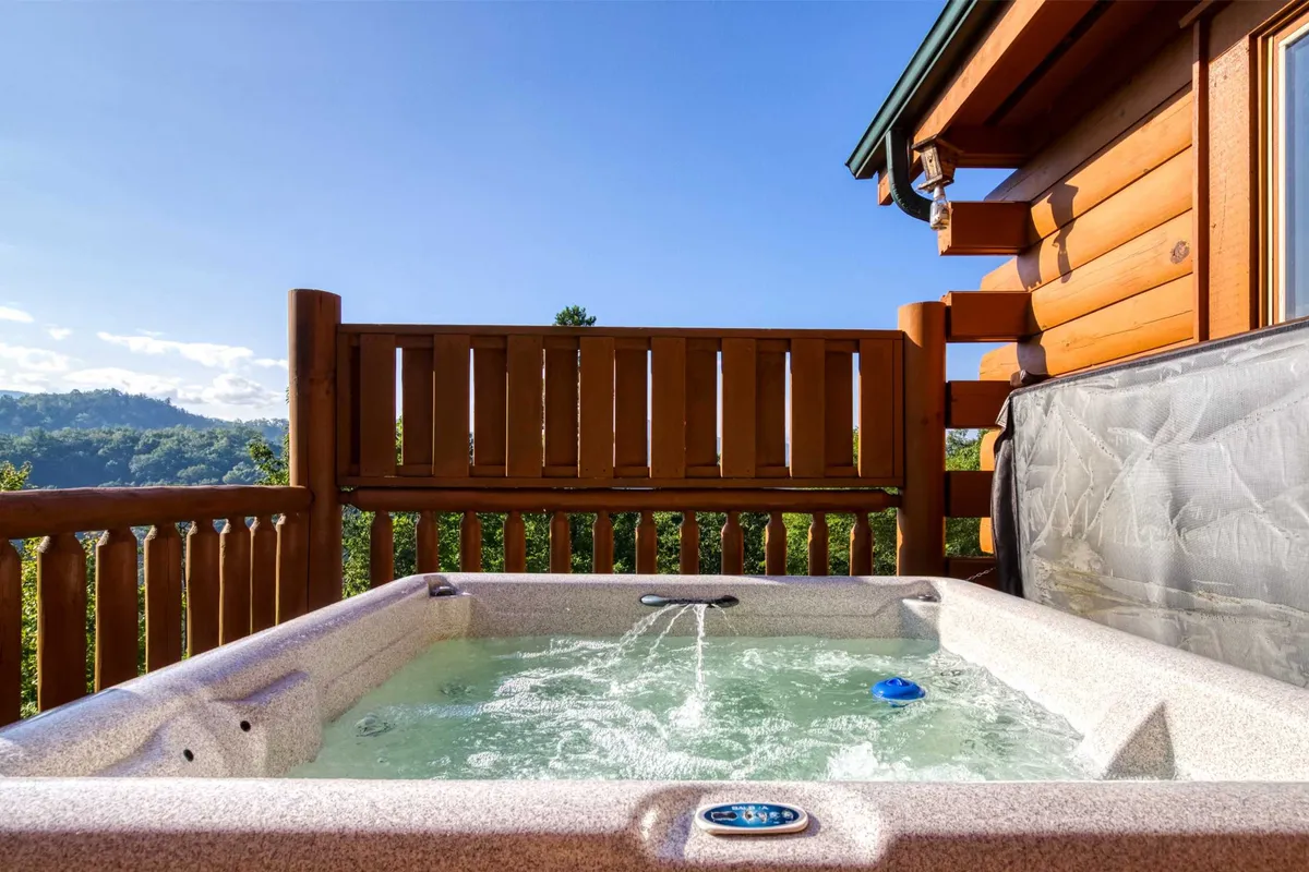 This image showcases a private outdoor hot tub set against a scenic mountain backdrop, with wooden railings and a tranquil atmosphere that hints at stargazing or unwinding at sunset. The hot tub area is secluded and perfectly positioned for picturesque views, inviting couples to relax and reconnect in luxury.