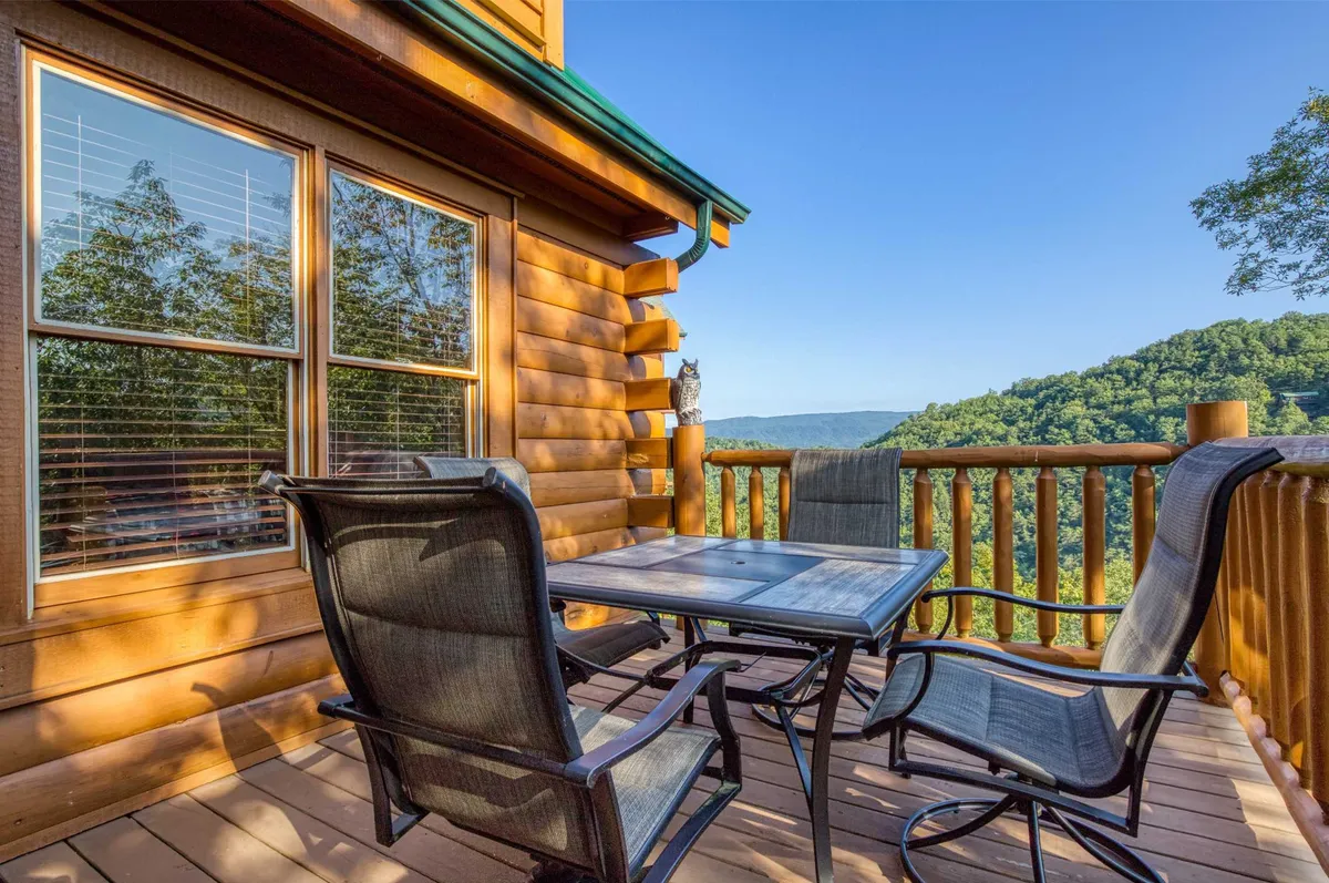 A wooden deck with comfortable outdoor seating and table offering sweeping mountain views. The space is set up for dining, socializing, or simply soaking in the scenic surroundings—ideal for barbecues or quiet gatherings after exploring the nearby attractions.